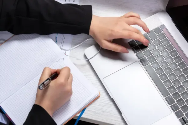 front-view-girl-taking-notes-writing-down-notes-front-table-with-schedules-graphics-using-laptop-job-business-activity