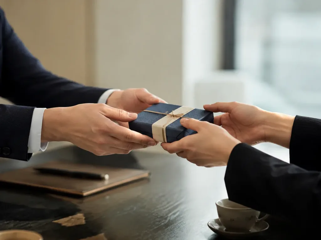 Business professionals respectfully exchanging a small wrapped gift across a meeting table in China.