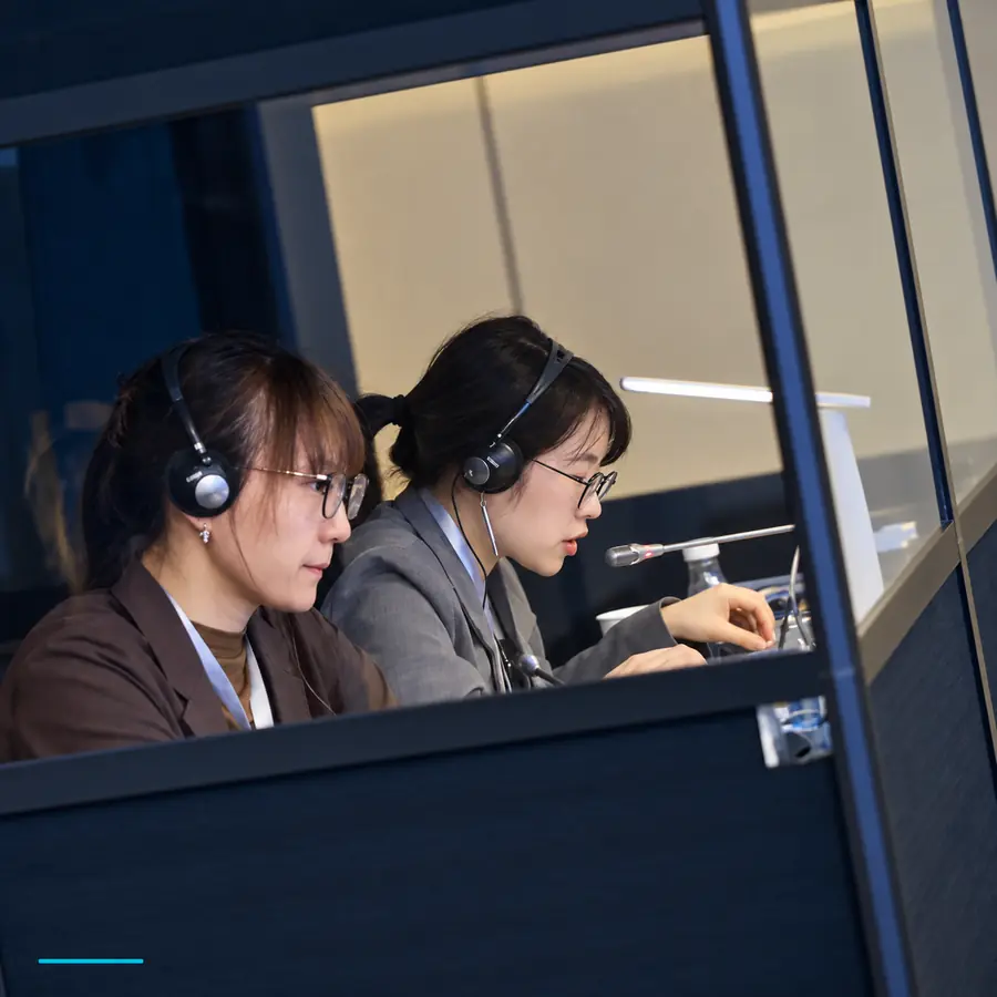 HI-COM simultaneous interpreters working in an interpretation booth at a business event in China