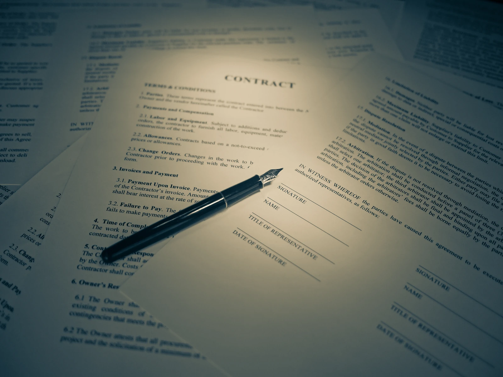 Fountain pen resting across English-language contract forms and a signature page.