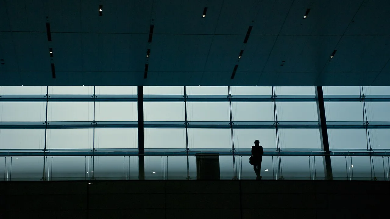 Voyageur en silhouette devant les baies vitrées de la gare de Shanghai Hongqiao.