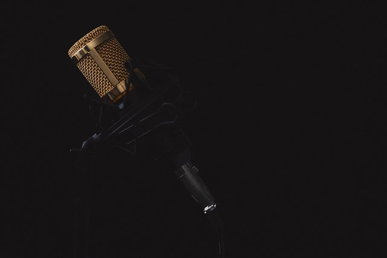 Microphone de studio éclairé sur un fond sombre.