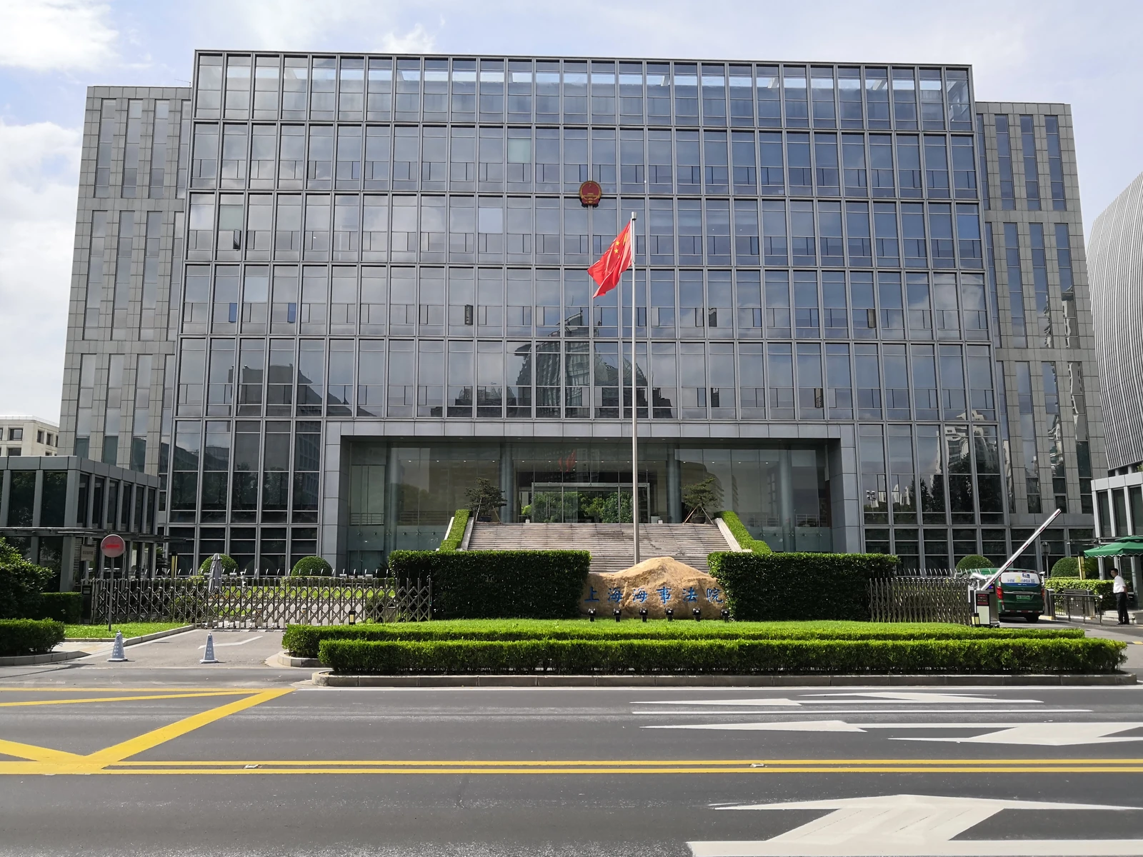 Glass-fronted Shanghai Maritime Court building with its main entrance and landscaped forecourt.