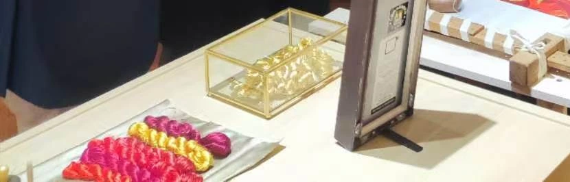 Pink and gold decorative threads, a gold display box and small workshop materials on a table.